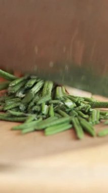 Kadın elleri ahşap kesme tahtasıyla taze biberiye doğruyor.