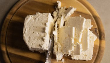 Tahta kesme tahtasında dilimlenmiş beyaz peynir.