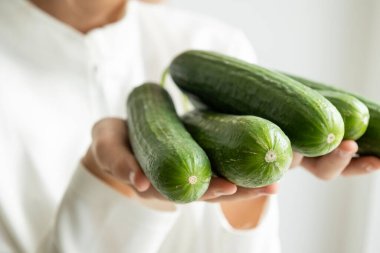 Hafif arka planda salatalık tutan kız sağlıklı beslenme konsepti