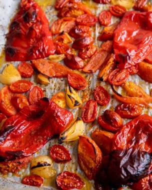 Kızarmış domates, kırmızı çan biberi, soğan, ve tepside sarımsak.