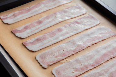 Pişirme tepsisindeki Parşömen Kağıdındaki Çiğ Pastırma Şeritleri Pişmeye Hazır