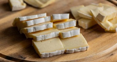 Dilimlenmiş peynirli peynirin ahşap kesim tahtasına yakın çekimi Yumuşak peynir hazırlama