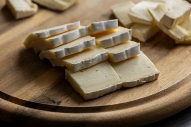 Dilimlenmiş peynirli peynirin ahşap kesim tahtasına yakın çekimi Yumuşak peynir hazırlama