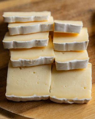 Dilimlenmiş peynirli peynirin ahşap kesim tahtasına yakın çekimi Yumuşak peynir hazırlama