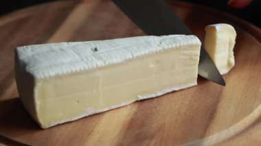 Tahta kesim tahtasında peynir dilimleyen kadın aperatifi.