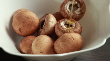 Bir kasede zeytinyağı, tuz ve biber ile baharatlı çiğ mantar.