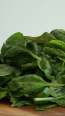 Tahta kesme tahtasının üzerinde parlak beyaz bir arka planı olan taze ıspanak yaprakları yakın plan.