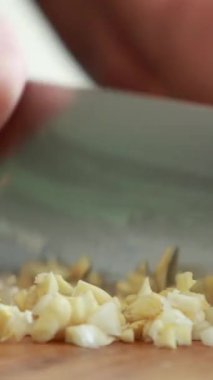 Makro yakın plan sarımsak karanfilleri kesim tahtasında doğranıyor.