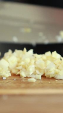 Makro yakın plan sarımsak karanfilleri kesim tahtasında doğranıyor.