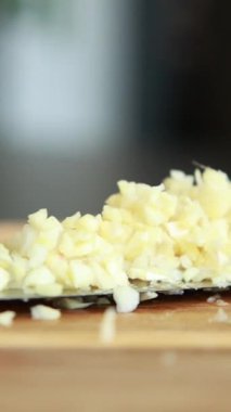 Makro yakın plan sarımsak karanfilleri kesim tahtasında doğranıyor.