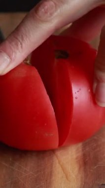 Tahta kesim tahtasında büyük, sulu domates dilimleme, yakın çekim yiyecek hazırlama.