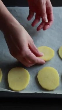 Parşömen kağıdıyla fırın tepsisinde çiğ patates çemberleri düzenleniyor