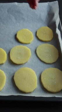 Parşömen kağıdıyla fırın tepsisinde çiğ patates çemberleri düzenleniyor