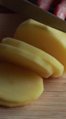 Soyulmuş çiğ patatesleri tahta kesme tahtasındaki yuvarlak dairelere dilimlemek