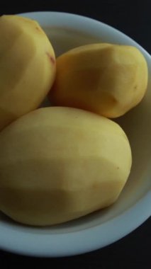 Soyulmuş çiğ patatesleri tahta kesme tahtasındaki yuvarlak dairelere dilimlemek