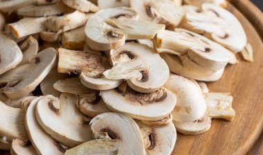 Tahta kesim tahtasında dilimlenmiş çiğ beyaz düğme mantarları