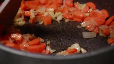 Doğranmış soğan ve havuç kızartma kabında yağ içinde cızırdıyor