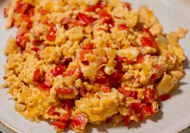 Çırpılmış yumurta soğan ve kırmızı dolma biberle pişirilir. Taze malzemelerle yapılan sağlıklı bir protein kahvaltısının yakından görüntüsü.