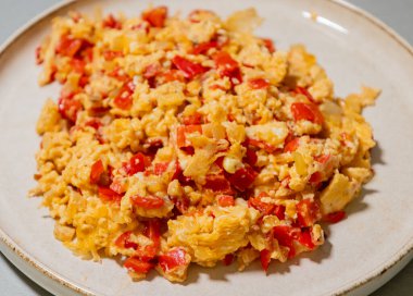 Çırpılmış yumurta soğan ve kırmızı dolma biberle pişirilir. Taze malzemelerle yapılan sağlıklı bir protein kahvaltısının yakından görüntüsü.