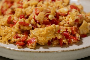 Çırpılmış yumurta soğan ve kırmızı dolma biberle pişirilir. Taze malzemelerle yapılan sağlıklı bir protein kahvaltısının yakından görüntüsü.