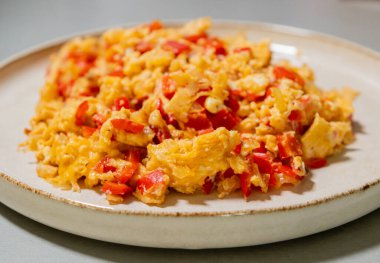 Çırpılmış yumurta soğan ve kırmızı dolma biberle pişirilir. Taze malzemelerle yapılan sağlıklı bir protein kahvaltısının yakından görüntüsü.