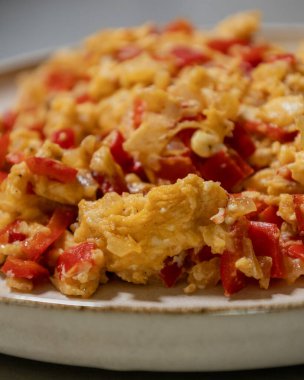 Çırpılmış yumurta soğan ve kırmızı dolma biberle pişirilir. Taze malzemelerle yapılan sağlıklı bir protein kahvaltısının yakından görüntüsü.