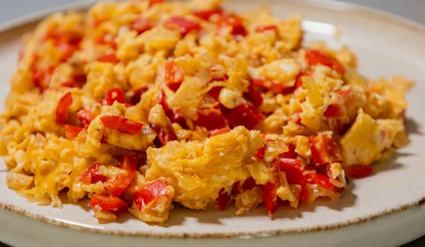 Çırpılmış yumurta soğan ve kırmızı dolma biberle pişirilir. Taze malzemelerle yapılan sağlıklı bir protein kahvaltısının yakından görüntüsü.