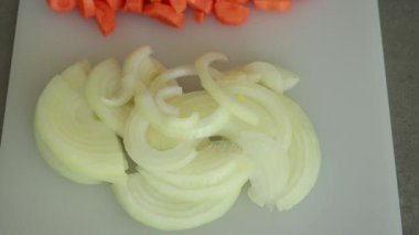 Dilimlenmiş soğan ve havuçların yakın çekim görüntüsü pişirmeye hazır. Sağlıklı yemek hazırlama, sebze hazırlama ve taze malzeme kavramları için ideal.