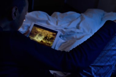 genç adam bir film ya da onun tableti bir dizi izlerken yatakta