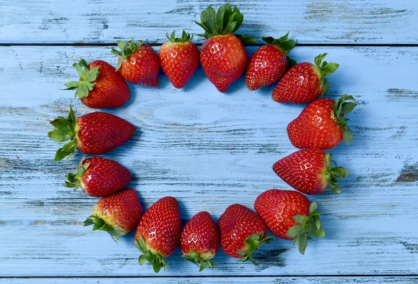 Fresas formando un círculo sobre una superficie de madera azul — Foto de Stock