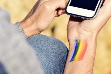 adam bileğini bir smartphone kullanarak bir gökkuşağı bayrağı ile