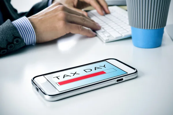 Text tax day in a smartphone at the office — Stock Photo, Image