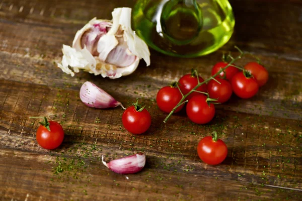 Azeite, tomate cereja e alho sobre uma mesa de madeira — Fotografia de Stock