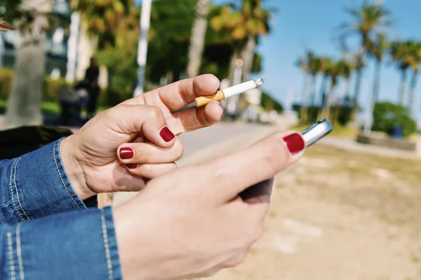 Jovem mulher fumando enquanto usa um smartphone — Fotografia de Stock