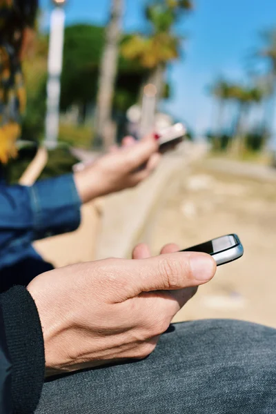 Jonge man en vrouw met behulp van hun smartphones — Stockfoto