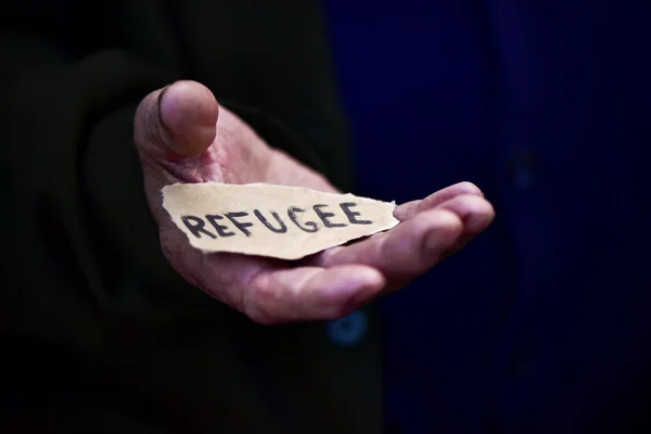 Anciano con un papel con la palabra refugiado — Foto de Stock