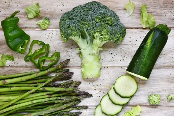 Rauwe groene groenten op een rustieke witte tafel — Stockfoto