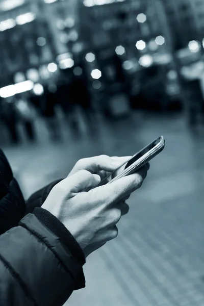 Jovem usando seu smartphone na rua à noite — Fotografia de Stock