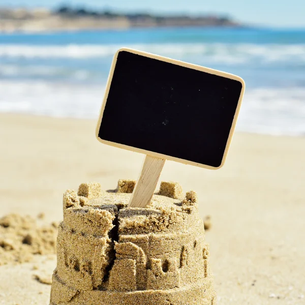 Enseigne vierge surplombant un château de sable — Photo