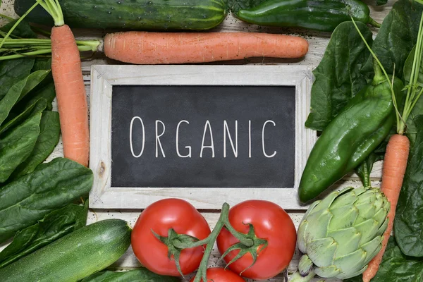 Légumes crus et texte bio sur un tableau — Photo