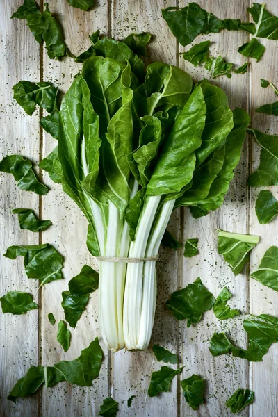 Raw chard leaves on a rustic white table — Stock Photo, Image