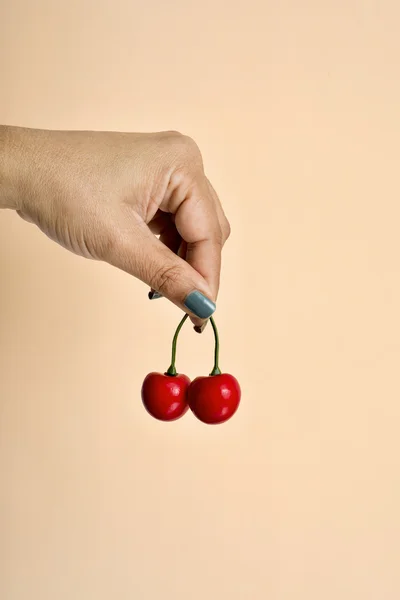 Jovem segurando algumas cerejas falsas — Fotografia de Stock