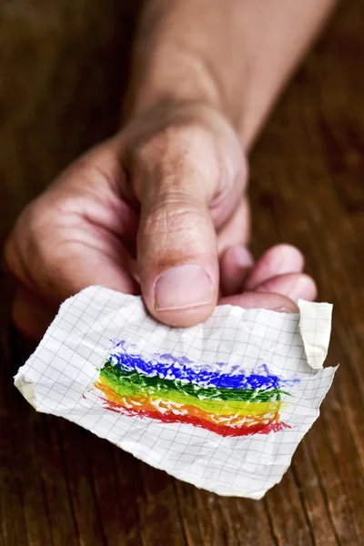 Hombre con un pedazo de papel con una bandera de arco iris — Foto de Stock