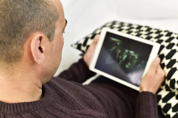 Ung man tittar på en film eller en serie i sin tablett — Stockfoto