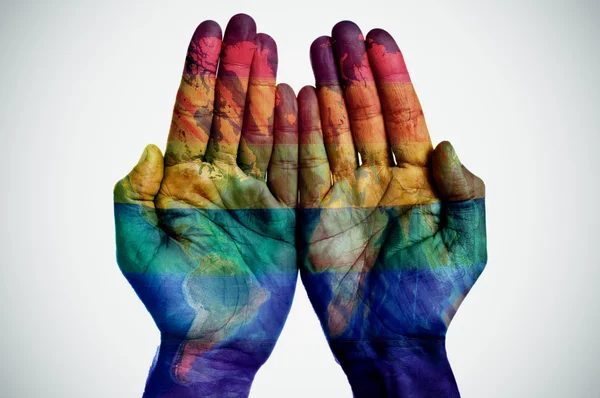 Världen karta och rainbow flag i händerna — Stockfoto