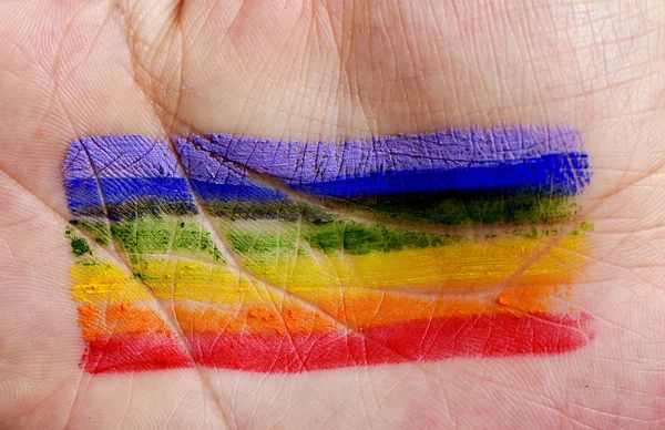 Homem com uma bandeira do arco-íris pintado em sua mão — Fotografia de Stock