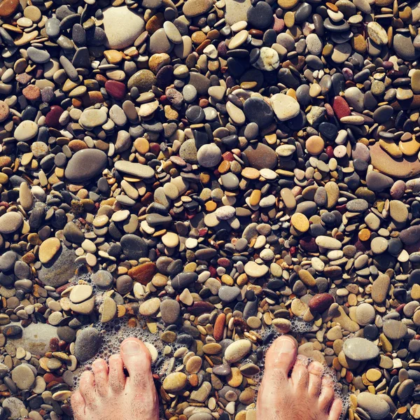 Jeune homme au bord de la mer d'une plage de galets — Photo