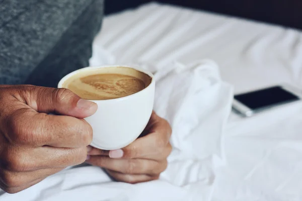 Молодой человек, пьющий кофе в постели — стоковое фото