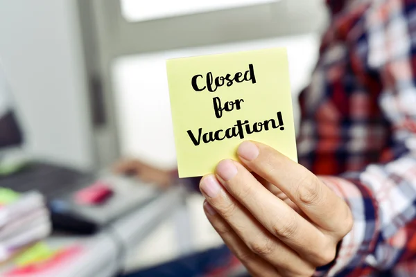 Man shows a note with the text closed for vacation — Stock Photo, Image