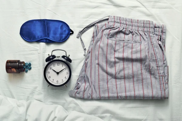 Máscara para dormir, comprimidos para dormir, despertador e pijama — Fotografia de Stock